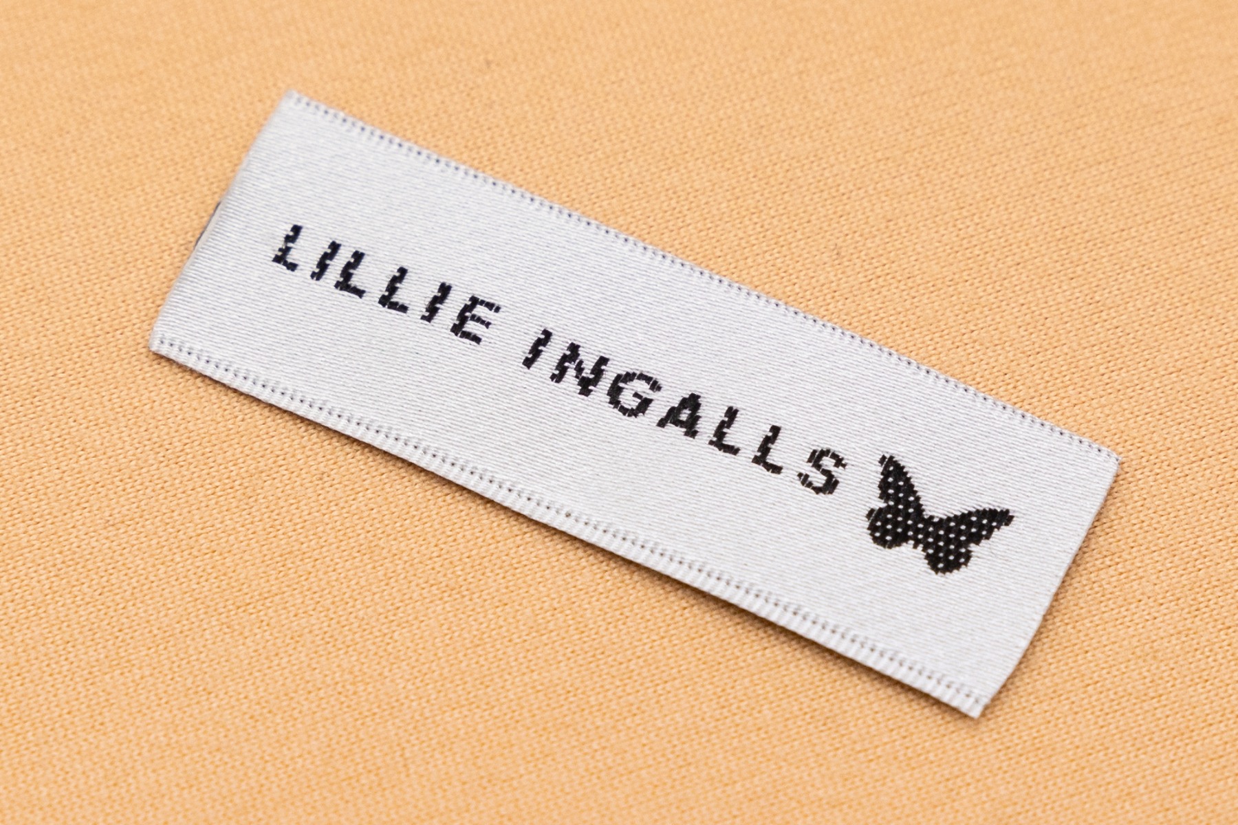 Close-up of satin clothing label showing shiny reflective surface and smooth finish