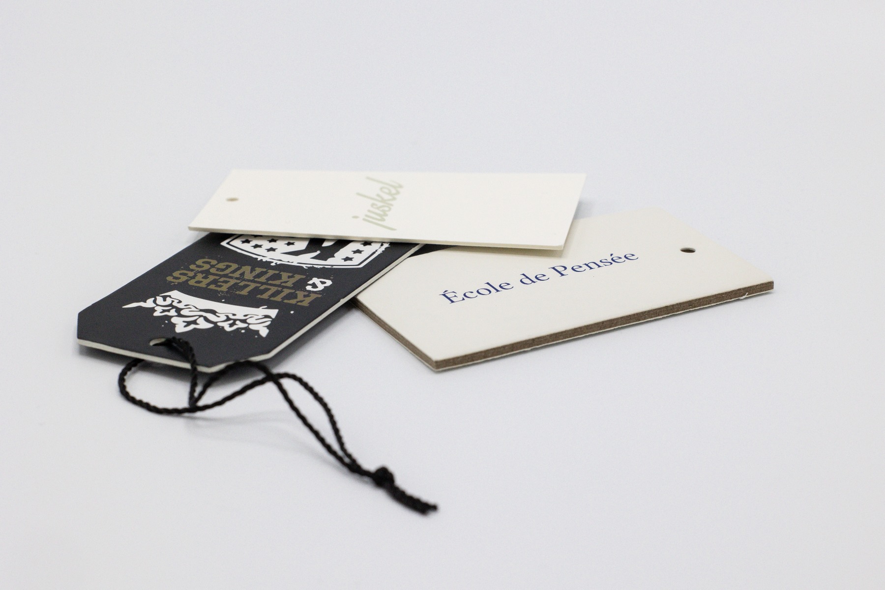 Custom hang tags in various shapes and finishes displayed on a white surface